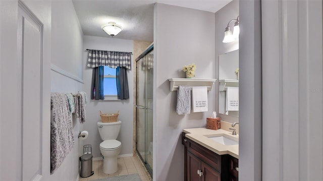 bathroom with vanity, toilet, tile patterned floors, and a shower with shower door