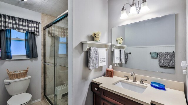 bathroom with vanity, toilet, a textured ceiling, and a shower with door