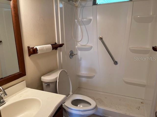 bathroom featuring vanity, a shower, and toilet