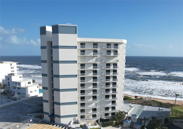 view of building exterior featuring a water view and a beach view