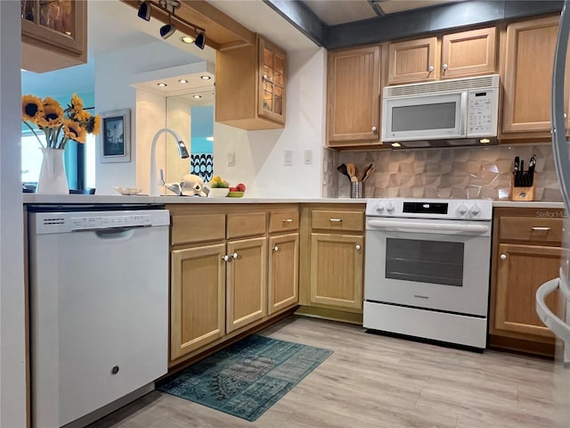 kitchen with white appliances, light hardwood / wood-style floors, tasteful backsplash, and sink