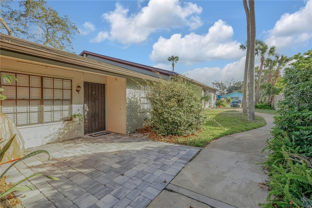 property entrance with a patio and a lawn