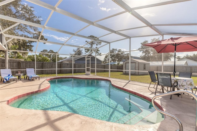 view of pool featuring a patio, glass enclosure, a shed, and a lawn