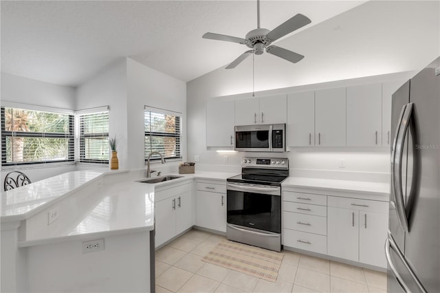 kitchen featuring appliances with stainless steel finishes, sink, kitchen peninsula, lofted ceiling, and white cabinets