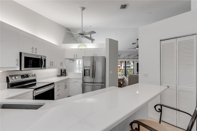 kitchen with a breakfast bar, white cabinetry, kitchen peninsula, and stainless steel appliances