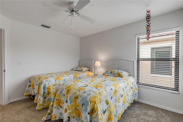 bedroom featuring a textured ceiling, light colored carpet, and ceiling fan