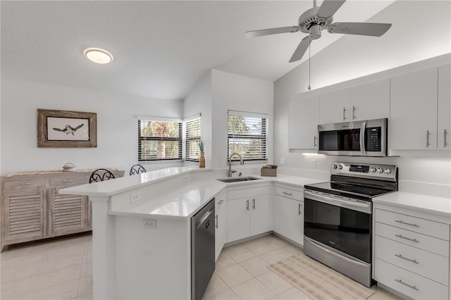 kitchen featuring sink, kitchen peninsula, stainless steel appliances, vaulted ceiling, and white cabinets