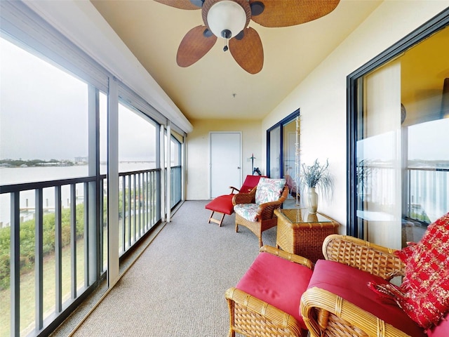 sunroom / solarium with a water view and ceiling fan