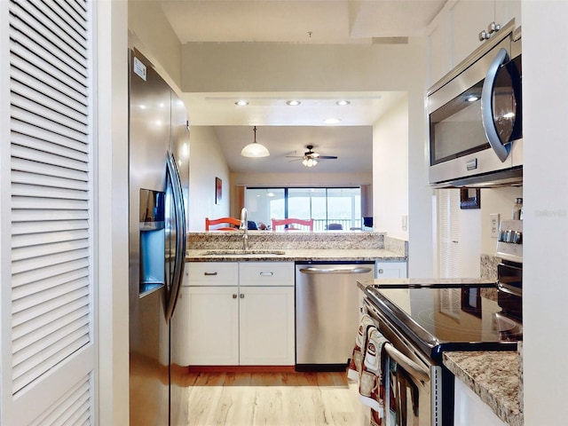 kitchen featuring light stone counters, stainless steel appliances, sink, white cabinets, and light hardwood / wood-style flooring