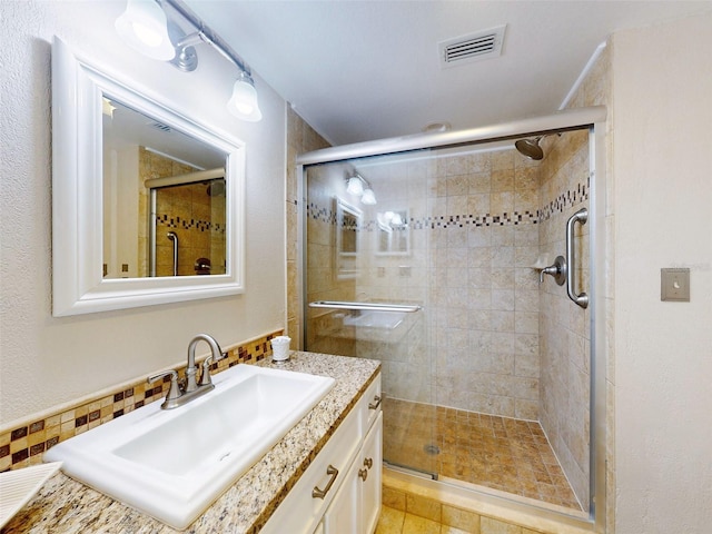 bathroom with a shower with shower door and vanity