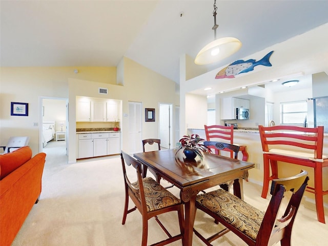 dining area with high vaulted ceiling, light carpet, and separate washer and dryer