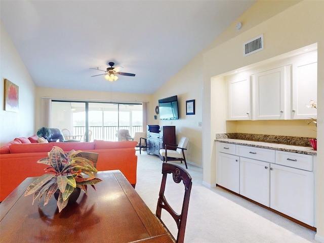 carpeted dining room with ceiling fan and lofted ceiling