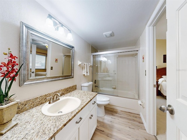 full bathroom featuring toilet, vanity, hardwood / wood-style floors, and enclosed tub / shower combo