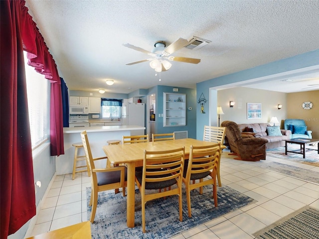 tiled dining room with ceiling fan, a textured ceiling, and sink