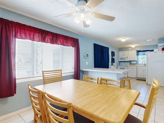 tiled dining room with sink, a textured ceiling, and ceiling fan