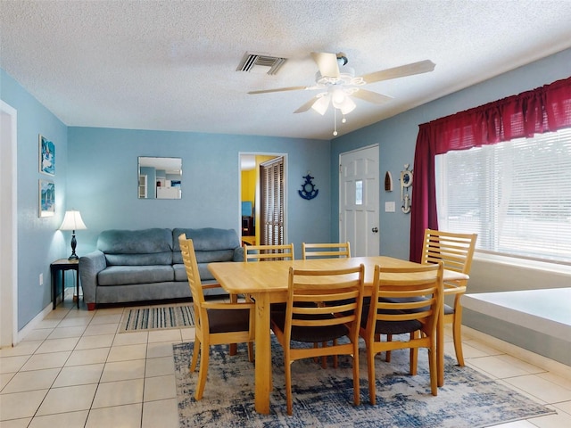 tiled dining room featuring a textured ceiling and ceiling fan