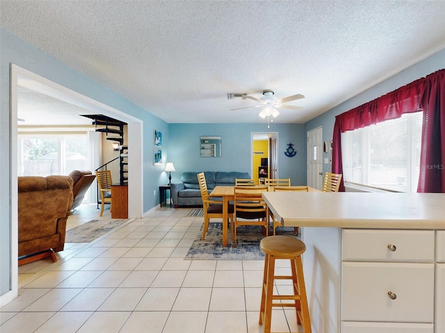 tiled dining space with a textured ceiling, a healthy amount of sunlight, and ceiling fan