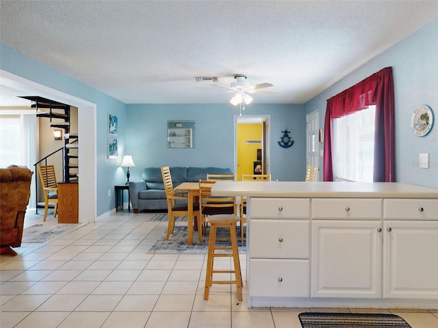 tiled dining room featuring a textured ceiling and ceiling fan