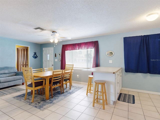 dining area with light tile patterned flooring, ceiling fan, and a textured ceiling