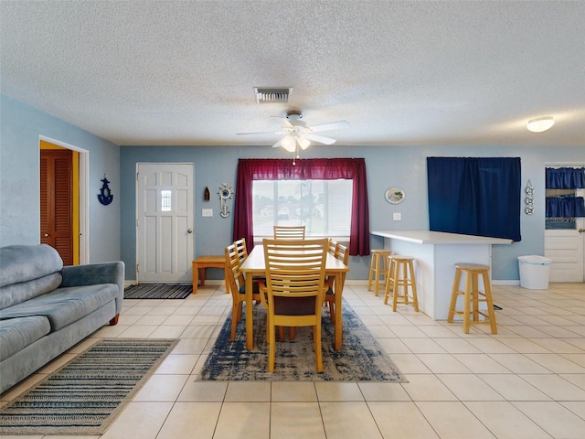 dining room with a textured ceiling, light tile patterned flooring, and ceiling fan