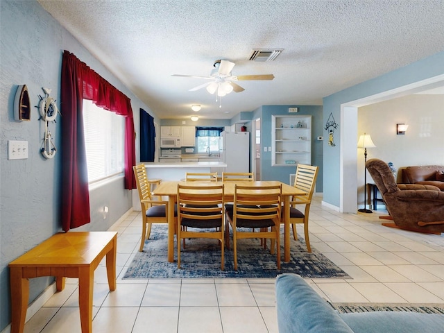 tiled dining area with a wealth of natural light, a textured ceiling, and ceiling fan