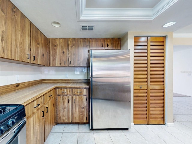 kitchen with crown molding, range with electric cooktop, stainless steel fridge, a tray ceiling, and light tile patterned flooring