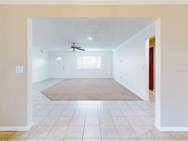 empty room with light tile patterned floors, ceiling fan, and crown molding