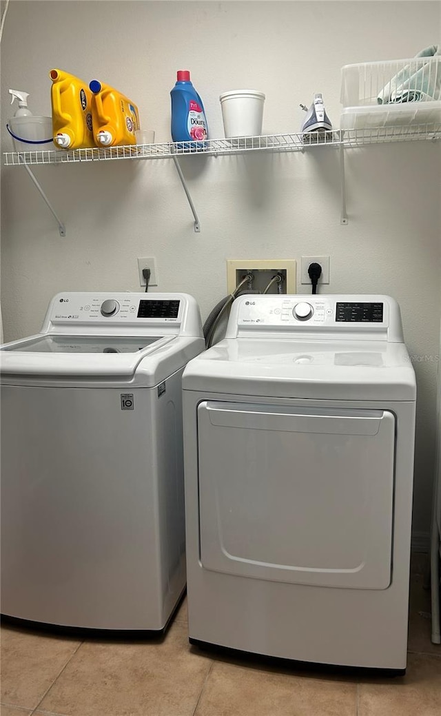 washroom featuring light tile patterned floors, washing machine and dryer, and laundry area