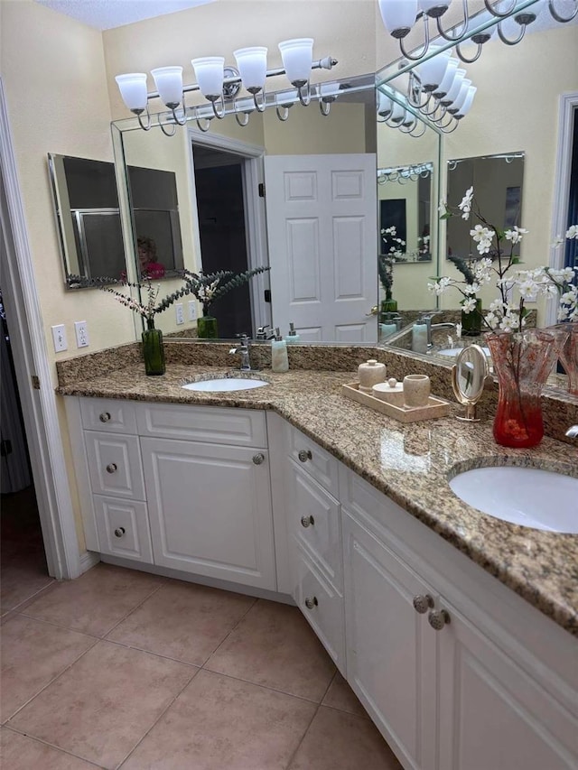 bathroom featuring tile patterned flooring, a chandelier, double vanity, and a sink