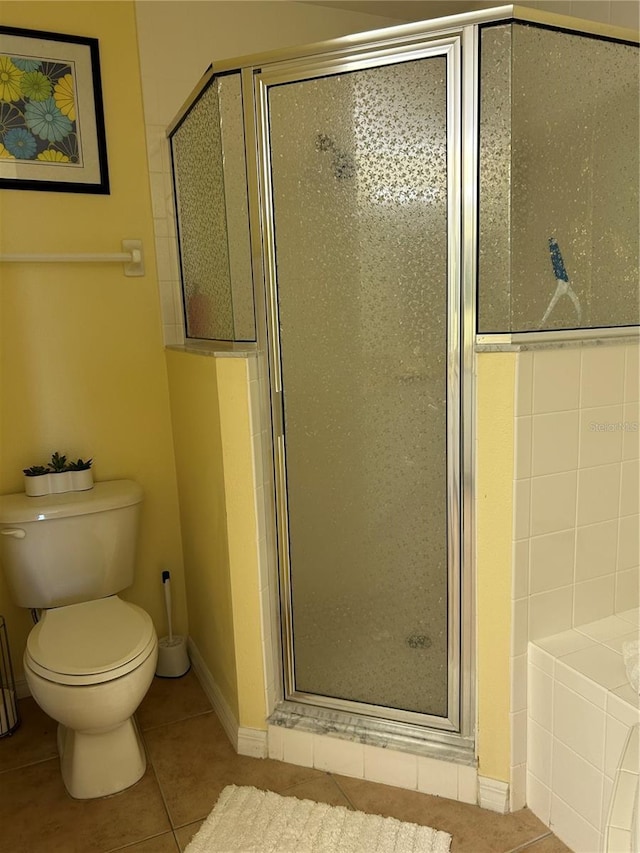 bathroom featuring tile patterned floors, toilet, baseboards, and a shower stall