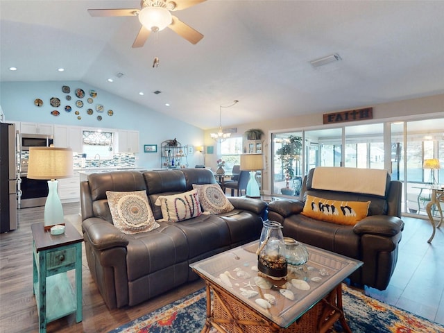 living room with hardwood / wood-style flooring, ceiling fan with notable chandelier, sink, and vaulted ceiling