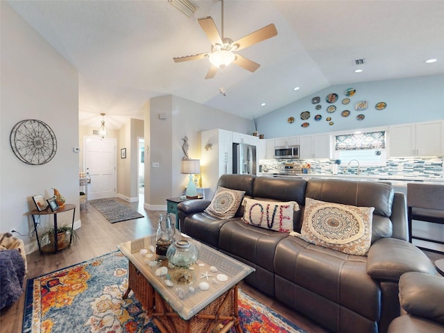 living room with light wood-type flooring, lofted ceiling, ceiling fan, and sink