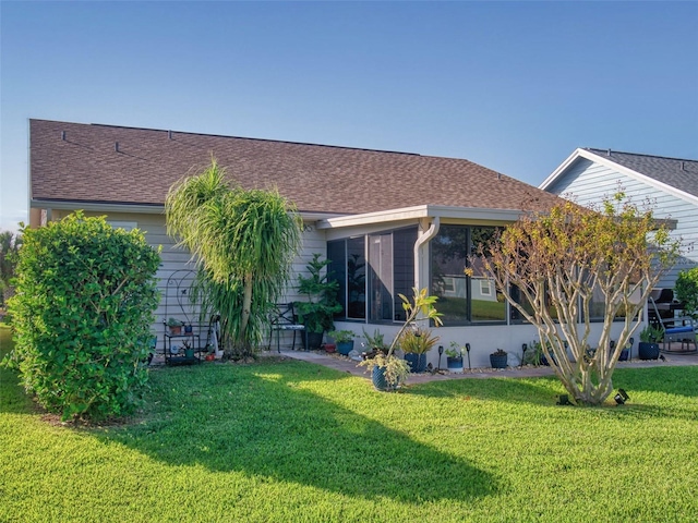 back of property featuring a sunroom and a lawn