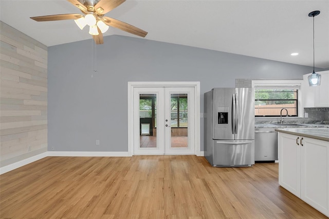 kitchen featuring stainless steel appliances, lofted ceiling, light hardwood / wood-style floors, white cabinets, and decorative light fixtures