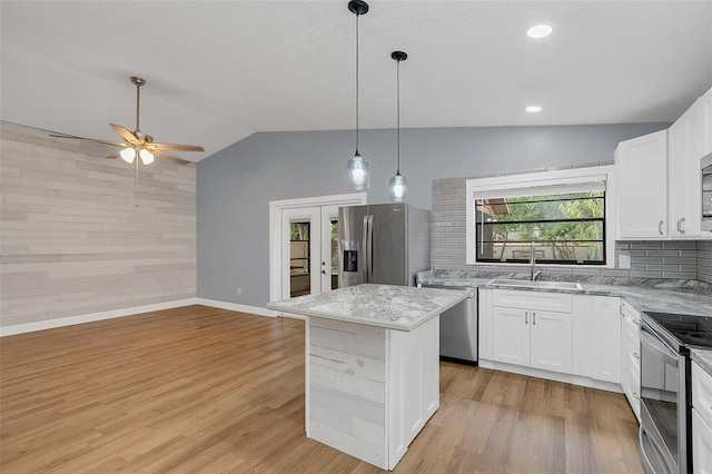 kitchen with a kitchen island, appliances with stainless steel finishes, sink, vaulted ceiling, and white cabinets