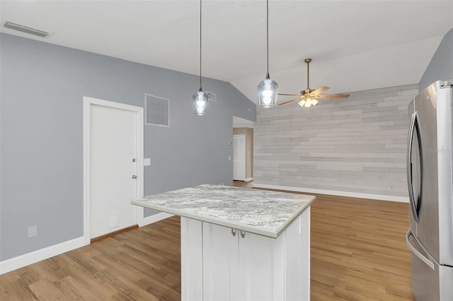 kitchen featuring ceiling fan, hanging light fixtures, lofted ceiling, stainless steel fridge, and light wood-type flooring