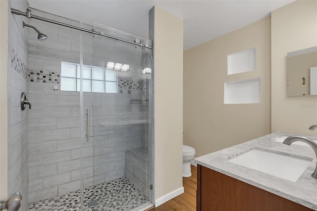 bathroom with toilet, an enclosed shower, vanity, and wood-type flooring