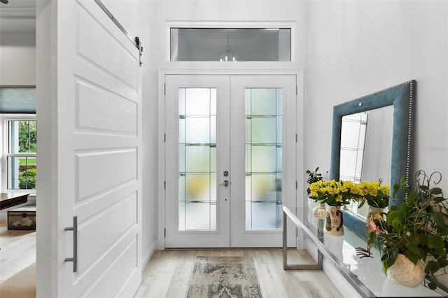 doorway to outside with light wood-type flooring, a barn door, and french doors