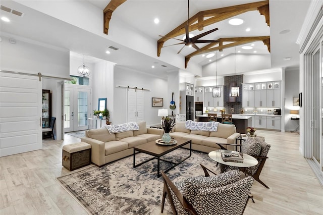 living room with a barn door, light hardwood / wood-style flooring, and high vaulted ceiling