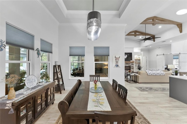 dining room with a towering ceiling, a barn door, light hardwood / wood-style flooring, and ceiling fan