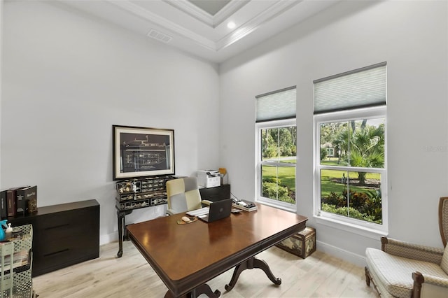 office area with a raised ceiling, ornamental molding, and light wood-type flooring