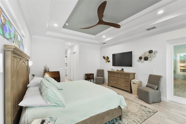 bedroom featuring ornamental molding, ceiling fan, a tray ceiling, and light hardwood / wood-style floors