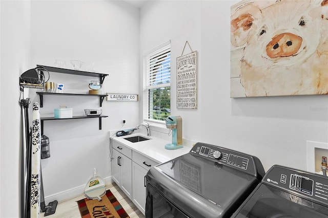 clothes washing area featuring cabinets, light wood-type flooring, separate washer and dryer, and sink