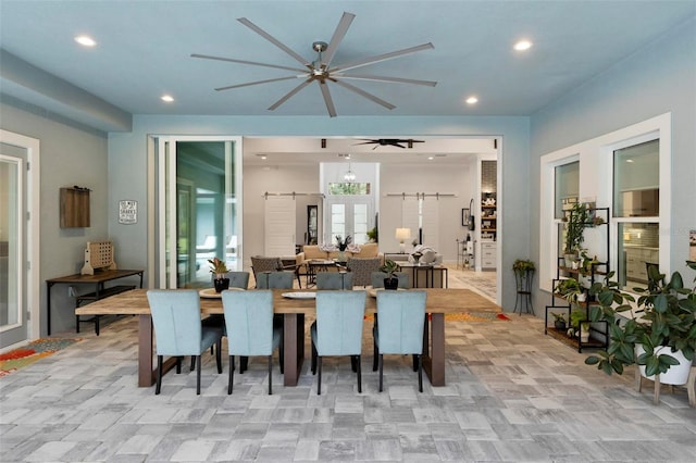 dining space featuring ceiling fan and a barn door