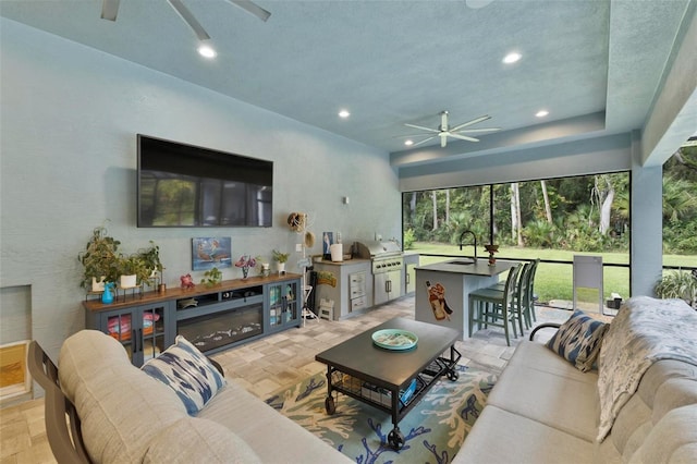 living room with a textured ceiling, light parquet flooring, ceiling fan, and sink