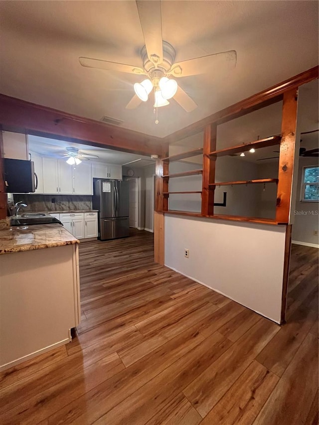 kitchen featuring stainless steel refrigerator, white cabinetry, light stone counters, ceiling fan, and dark wood-type flooring