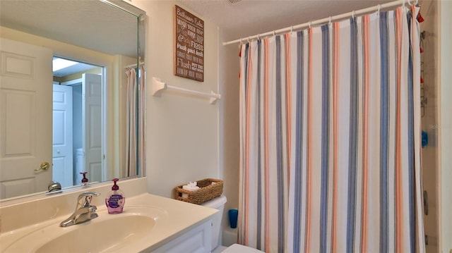 bathroom featuring walk in shower, vanity, and toilet