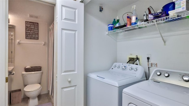 clothes washing area with washing machine and dryer and tile patterned floors