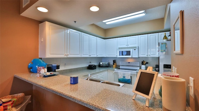 kitchen with kitchen peninsula, white appliances, and white cabinets