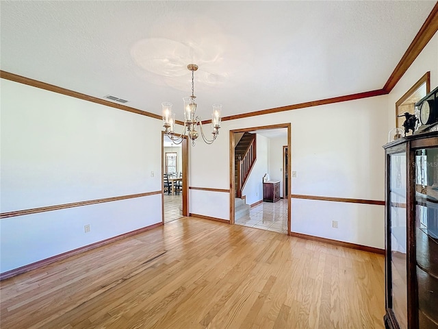 spare room featuring ornamental molding, a textured ceiling, light hardwood / wood-style flooring, and a notable chandelier